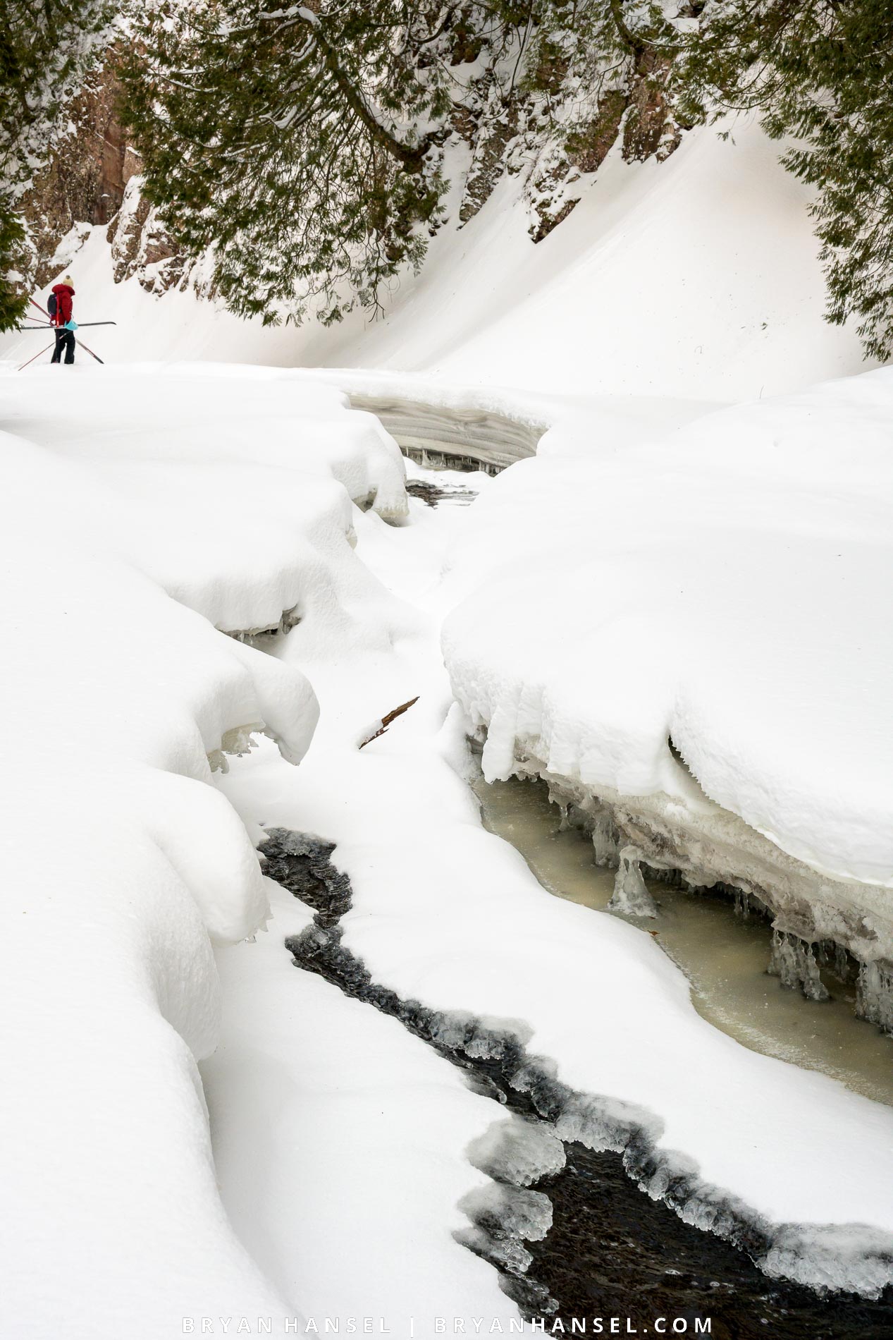 Photo of a frozen river and a cross country skier walking a dangerous section.