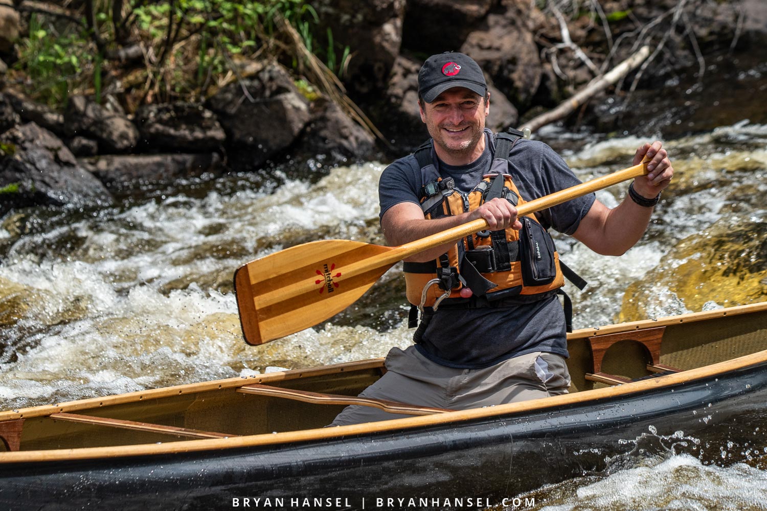 whitewater canoeist doing a cross bow draw in a whitewater canoe situation. 