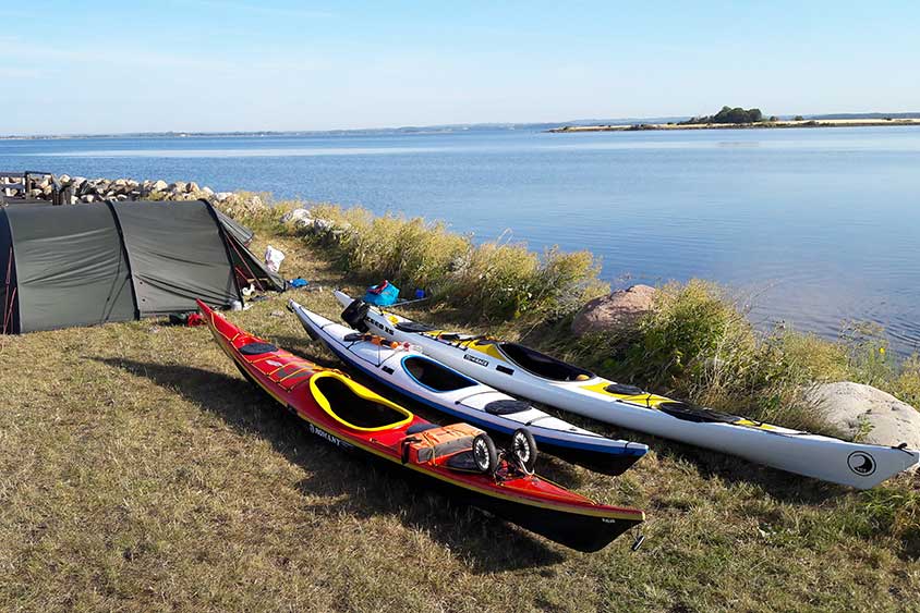 three kayaks sitting on a beach next to a tent